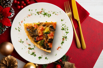 Wall Mural - Piece of roasted vegetarian vegetable quiche. Top view table with Christmas decorations.