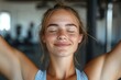 © Milos - A woman with closed eyes and a peaceful smile, standing in a fitness center, embodies tranquility and contentment, exuding a sense of well-being and beauty.