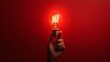 © MaxStock - Hand holding a vintage light bulb on a red background