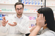 © InsideCreativeHouse - Confident smart male pharmacist druggist advising remedy, painkillers, drugs, medicines, pills for a female customer client buyer suffering from headache migraine in pharmacy drugstore