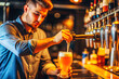 © isavira - Barman young guy pouring beer into a glass from the tap behind the bar counter close-up, soft focus.