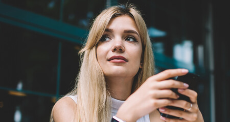 Dreamy freelancer with smartphone looking away