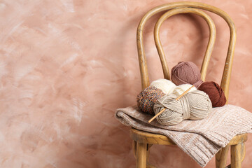 Poster - Different yarns, crochet hook and project on chair near beige wall. Space for text