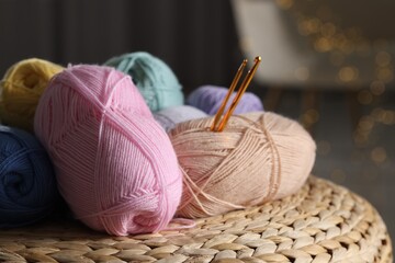 Poster - Knitting material. Skeins of soft yarn and crochet hooks on wicker surface indoors, closeup