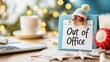 © Phakawan - A playful 'Out of Office' note displayed on a desk, adorned with a cute hat and sunglasses, capturing the festive spirit of a holiday break amidst a warm and cozy workspace setting.