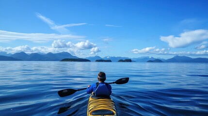 Canvas Print - Person kayaking in the open ocean with distant islands on the horizon