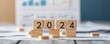 © JAKE STUDIO - Wooden blocks displaying the year 2024 on a desk with financial documents.