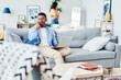 © BullRun - Serious African American man freelancer talking on mobile phone during remote job at modern home interior, dark skinned hipster guy making call while sitting on sofa at contemporary furniture