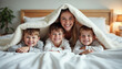 © Ali Hamza Tullah - Happy mother with sons lying in bed under blanket and throwing it off smiling at camera. Concept of family happiness, relaxing at home, having fun in bed, parent and cheerful kids