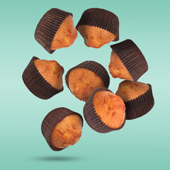 Wall Mural - Delicious muffins in air on turquoise background