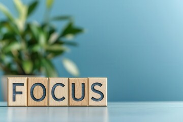 Wall Mural - focus spelled out in block letters on a table with green plant in the background.