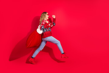 Poster - Full body portrait of nice young girl hold presents walk empty space isolated on new year xmas bright red color background