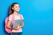 © Boston84 - A young girl is smiling and holding a laptop and her backpack
