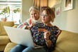 © Marko Geber - Two senior women shopping online using credit card on laptop at home