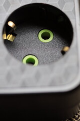 A close-up view of an electrical outlet with two green eyes.