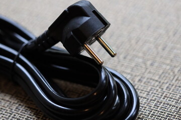 A close-up shot of a black power cord lying on a table.