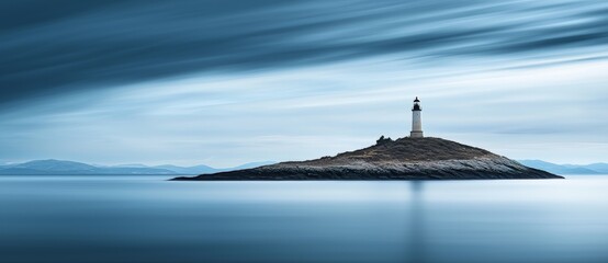 In a blurry cloudy sky background, a lighthouse and Agios Nikolaos church can be seen on Kea, Tzia island, Greece.