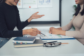 Collaborative Brainstorming: Two women, business partners, or colleagues, engage in a lively discussion, analyzing data and charts.