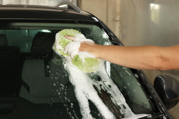 Wall Mural - Man washing car windshield with sponge indoors, closeup