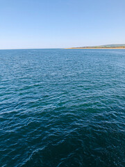 Wall Mural - seascape from kayak of clear blue ocean and island in distance and white fluffy clouds and blue sky