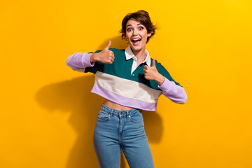 Canvas Print - Portrait of pretty nice young girl astonished show thumb up wear shirt isolated on yellow color background