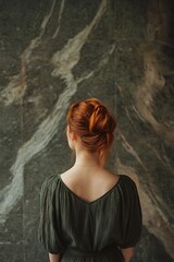 Back of redhead woman standing in front of abstract wall with vintage aesthetic