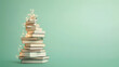 © almal - Alternative Christmas tree made from a stack of books. Stack of books in the shape of a Christmas tree, decorated with lights. Light green background. Modern, copy space, minimal