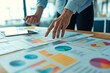 © vasyan_23 - Analyzing business data: hands gesturing over colorful charts and graphs in a modern office