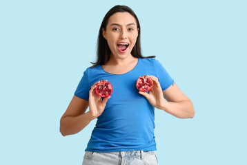 Canvas Print - Beautiful young woman with fresh pomegranate on blue background