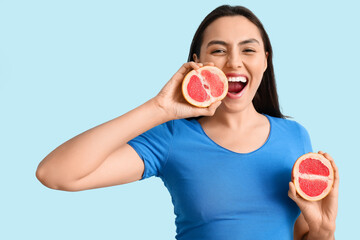 Poster - Beautiful young woman with fresh grapefruit on blue background