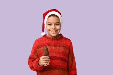 Poster - Cute little African-American boy with chocolate Santa Claus on lilac background