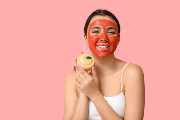 Wall Mural - Beautiful young woman with facial mask against pink background