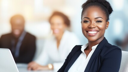 Poster - A woman in a business suit is smiling and sitting in front of a laptop