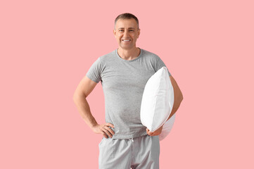 Poster - Handsome mature happy man in stylish pajamas with pillow on pink background