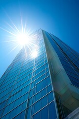 Wall Mural - Modern skyscraper reaching towards bright sun with blue sky. Architecture, business, success concept.