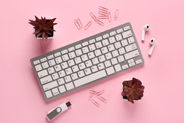 Wall Mural - Grey computer keyboard, earphones and flash drive on pink background. Top view