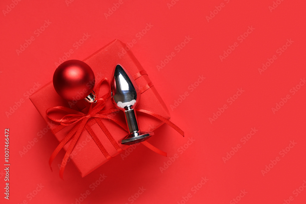 Anal plug, Christmas ball and gift box on red background