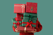 © Pixel-Shot - Woman holding stack of different Christmas gifts on color background