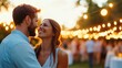 © LifeMedia - A couple smiles warmly at each other under twinkling string lights at an outdoor event, embodying joy, romance, and human connection in a vibrant setting.