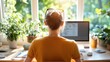 © LifeMedia - A person sits at a desk with plants and sunlight streaming through the window, emphasizing harmony, nature, and a tranquil work environment in a modern setup.