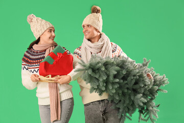 Canvas Print - Young couple with Christmas tree and gift box on green background