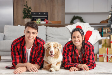 Canvas Print - Happy young couple in pajamas with dog lying at home on Christmas eve