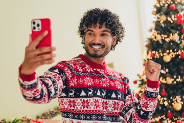 Poster - Photo of nice young man phone selfie raise fist illumination wear christmas pullover festive time apartment indoors