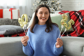 Wall Mural - Beautiful young woman with figure 2025 made of foil balloons in living room. Christmas celebration