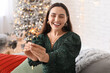 © Pixel-Shot - Happy young woman with Christmas sparkler in living room