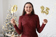 © Pixel-Shot - Happy young woman with figure 2025 made of foil balloons in living room. Christmas celebration