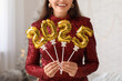 © Pixel-Shot - Young woman with figure 2025 made of foil balloons in living room. Christmas celebration