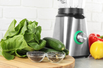 Healthy products and blender on grey table against white brick wall, closeup