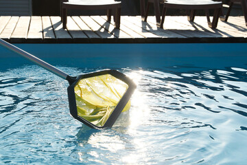 Canvas Print - Cleaning swimming pool with skimmer net at luxury resort