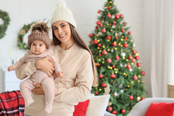 Wall Mural - Happy mother with her little baby in warm hats at home on Christmas eve